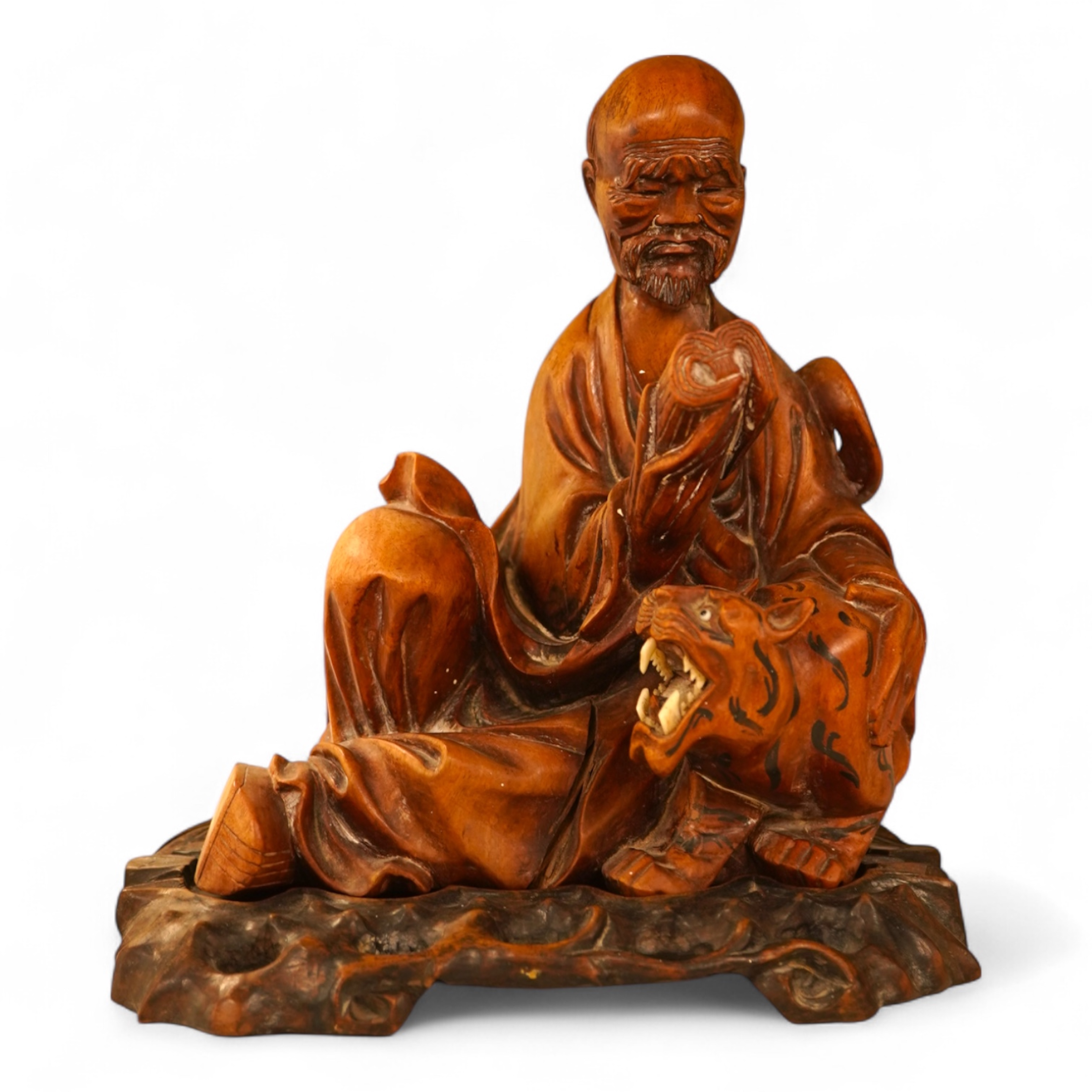 A Chinese hardwood carving of a seated luohan and tiger on hardwood stand, 24cm high including stand.
